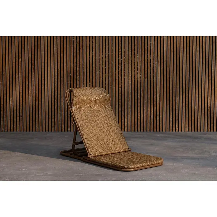 Ebuy24 Gartenliege Ellie - Braun, Naturmaterialien - Verstellbarer Liegestuhl aus geflochtenem Rattan mit geneigter Rückenlehne auf Betonboden vor einer Holzlamellenwand.