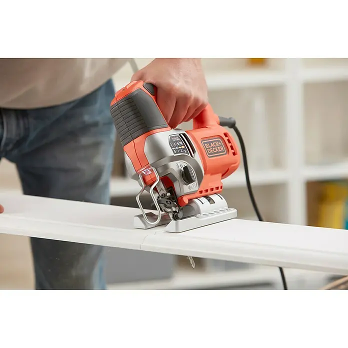 Black+Decker Sierra de calar eléctrica BES610K-QS - 1.000 /min - 3.100 /min, 90 mm - La sierra de calar Black+Decker corta un trozo de madera. La sierra de calar es naranja y gris, y tiene un mango negro.