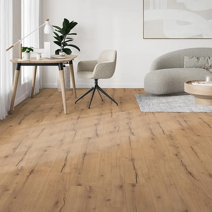 Parador Designboden Modular One - Eiche Trento Rustikal, Landhausdiele, 1.285 x 194 x 8 mm - Helles, braunes Holzfußboden mit dunklen Rissmustern in einem modernen Wohnraum mit Schreibtisch und Sofa.
