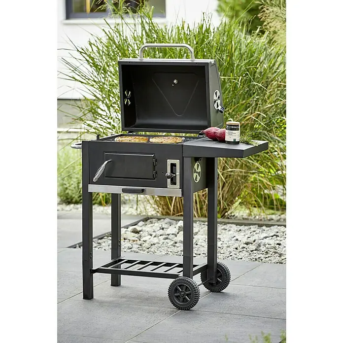Grillstar Holzkohlegrill Boston - Grillfläche (B x T): 45 x 32 cm, Schwarz - Hier ist ein Holzkohlegrill mit geöffnetem Deckel, Rost mit Speisen darauf und Gewürzen auf dem Seitentisch.
