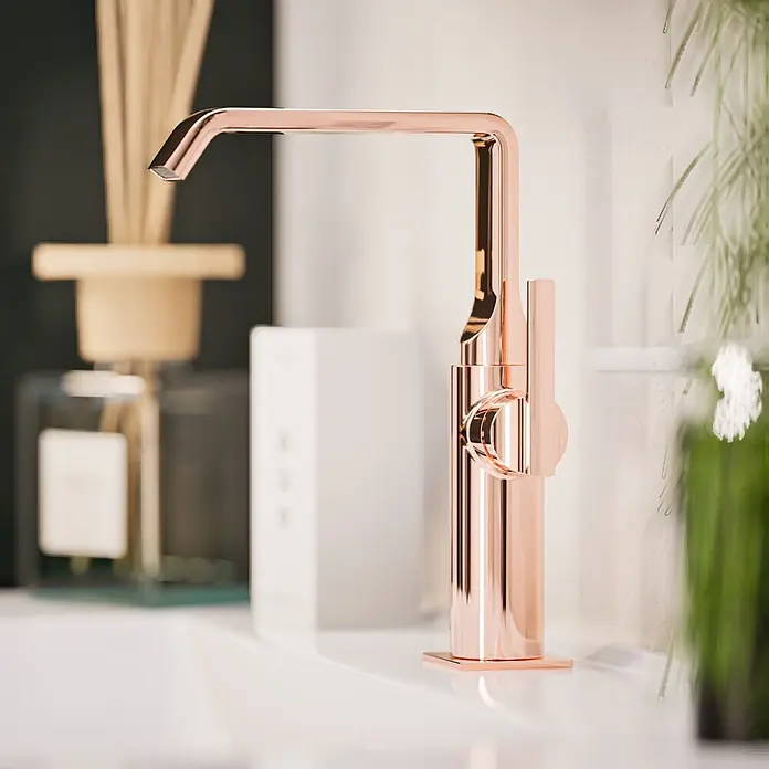 VitrA Suit Waschtischarmatur - Kupfer, Glänzend, Ohne Zugstange, Höhe: 25,7 cm - Eleganter Wasserhahn in Roségold mit schlankem Design, auf einem weißen Waschtisch installiert.