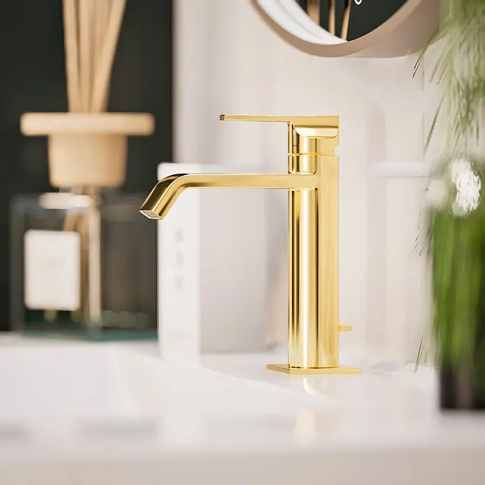 VitrA Suit Waschtischarmatur - Gold, Glänzend, Höhe: 19 cm - Moderner goldener Badarmatur auf einem weißen Waschbecken, mit unscharfem Dekor im Hintergrund.