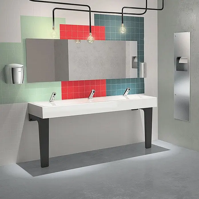 Delabie Waschbecken Delabie - Ohne Überlauf, Weiß - Modernes weißes Waschbecken mit schwarzen Stützen und drei integrierten Armaturen in einem zeitgenössischen öffentlichen Waschraum.