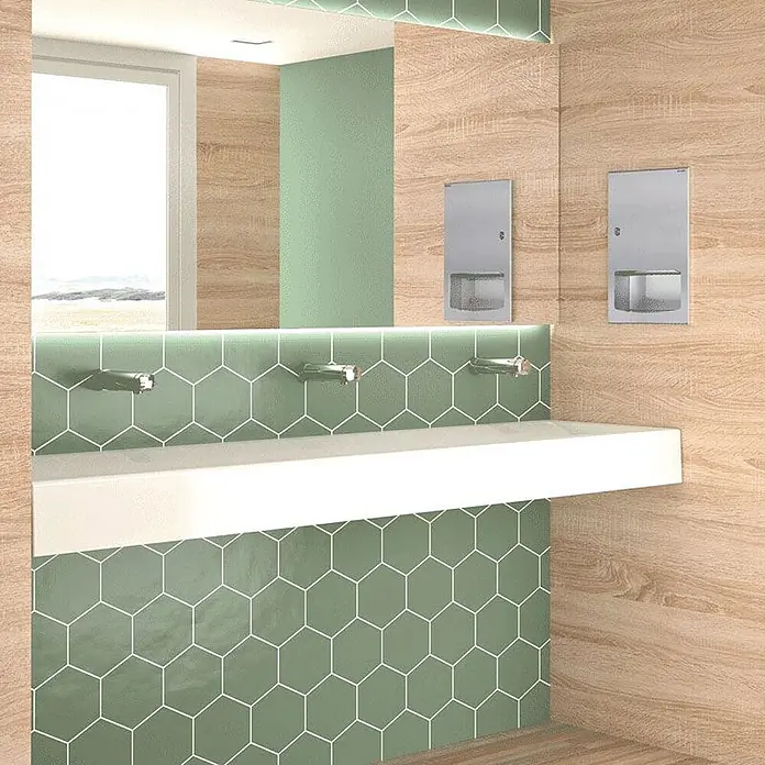Delabie Waschbecken Delabie - Ohne Überlauf, Weiß - Moderner öffentlicher Waschraum mit langem weißem Waschbecken, grünen sechseckigen Wandfliesen, Wandarmaturen und Seifenspendern.