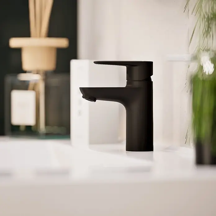 VitrA Flow Soft Waschtischarmatur - Schwarz, Höhe: 15 cm, Ohne Zugstange - Elegante mattschwarze Badarmatur mit Einhebel-Design, über einem weißen Waschbecken installiert.