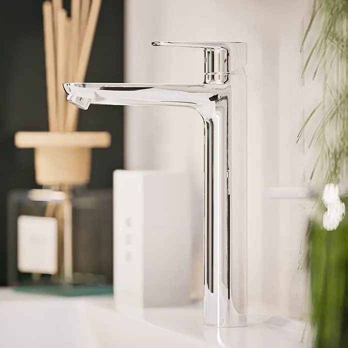 VitrA Flow Soft Waschtischarmatur - Höhe: 29,3 cm, Ohne Zugstange, Chrom - Chrom-Einhebel-Waschtischarmatur auf einem Waschbecken, mit Diffusor und Pflanze im Hintergrund.