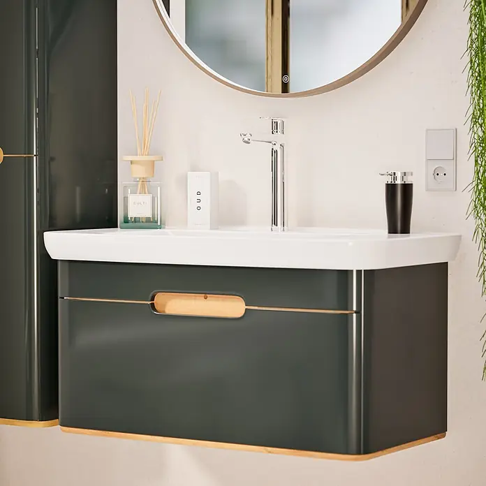 VitrA Flow Soft Waschtischarmatur - Höhe: 29,3 cm, Ohne Zugstange, Chrom - Moderne dunkelgraue Badkommode mit integriertem weißen Waschbecken, Holzgriff und Sockelblende, in einem modernen Badezimmer mit rundem Spiegel.