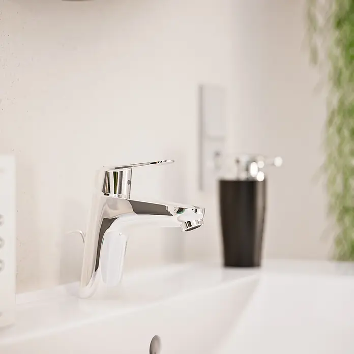 VitrA Flow Round Waschtischarmatur Eco - Höhe: 15 cm, Ausladung Armatur: 114 mm, Chrom - Moderner Chrom-Wasserhahn auf einem weißen Keramikwaschbecken.