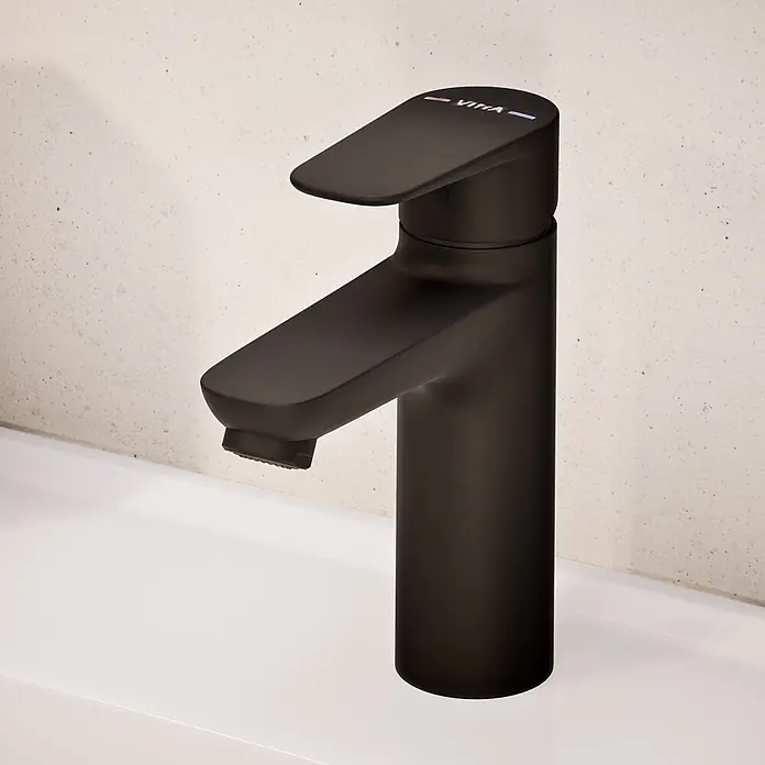 VitrA Flow Soft Waschtischarmatur - Schwarz, Höhe: 17 cm, Ohne Zugstange - Mattschwarze Einhebel-Waschtischarmatur mit flachem Auslauf, auf einem weißen Waschbecken vor heller Wand installiert.
