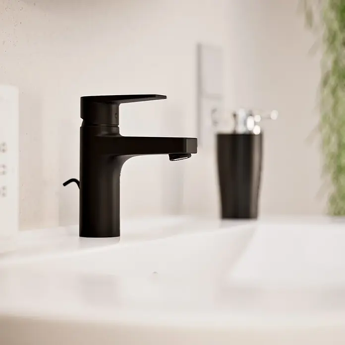 VitrA Flow Square Waschtischarmatur - Schwarz, Matt, Höhe: 15,6 cm, Mit Zugstange - Mattschwarze Einhebelarmatur in einem weißen Waschbecken, mit passendem schwarzen Seifenspender.