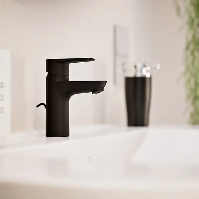 VitrA Flow Soft Waschtischarmatur - Schwarz, Höhe: 15 cm, Mit Zugstange - Mattschwarzer Wasserhahn mit schlankem Design, auf einem weißen Waschbecken in einem modernen Bad.