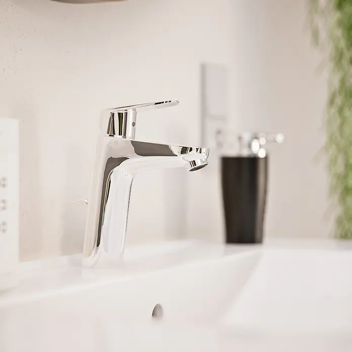 VitrA Flow Round Waschtischarmatur Eco - Höhe: 18 cm, Ausladung Armatur: 115 mm, Chrom, Mit Zugstange - Glänzende, verchromte Badezimmerarmatur auf einem weißen Waschbecken.