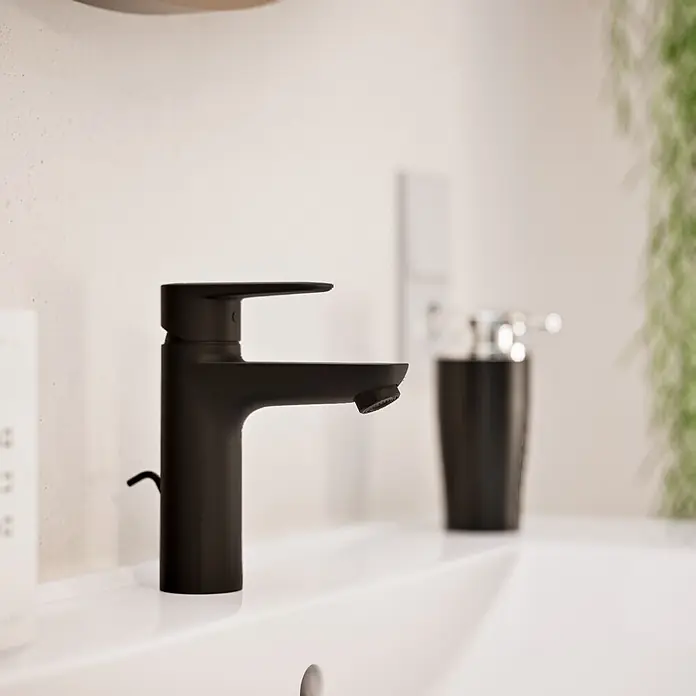 VitrA Flow Soft Waschtischarmatur - Schwarz, Höhe: 17 cm, Mit Zugstange - Ein mattschwarzer Einhebelmischer auf einem weißen Waschbecken in einem modernen Bad.