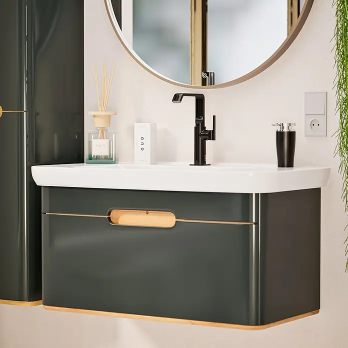 VitrA Suit Waschtischarmatur - Schwarz, Glänzend, Ohne Zugstange, Höhe: 25,7 cm - Dunkelgrüner Badunterschrank mit weißem Waschbecken, schwarzem Wasserhahn und rundem Spiegel, akzentuiert mit Holz- und Golddetails.