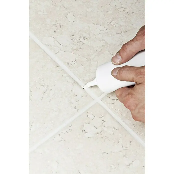 Knauf Fugenreparatur - Weiß, 250 g - Eine Hand füllt Fliesenfugen mit einer weißen Dichtmasse aus einer Tube, um das Badezimmer oder die Küche aufzufrischen.