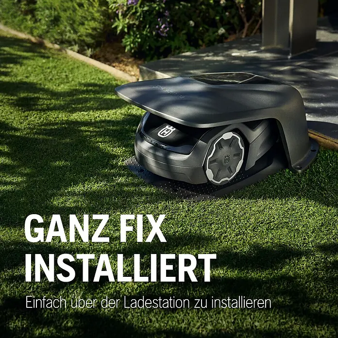 Husqvarna Mähroboter-Garage Aspire R4 - Grau, Aspire R4 - Dunkelgraue Schutzabdeckung über einer Roboter-Rasenmäher-Ladestation auf Rasen installiert.