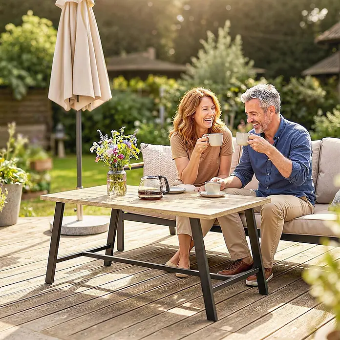 Outsunny Garten-Loungetisch - Braun, L x B x H: 100 x 55 x 45 cm - Ein Paar trinkt Kaffee im Freien an einem Holztisch mit Metallbeinen und einem Outdoor-Sofa mit hellen Polstern.