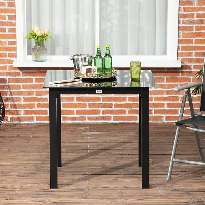 Outsunny Balkontisch mit verstellbare Fußstützen - L x B x H: 80 x 80 x 74 cm, Aluminium, Hartglas, Quadratisch, Schwarz - Quadratischer schwarzer Gartentisch mit schwarzer Glasplatte und Metallrahmen, auf einer Holzterrasse.