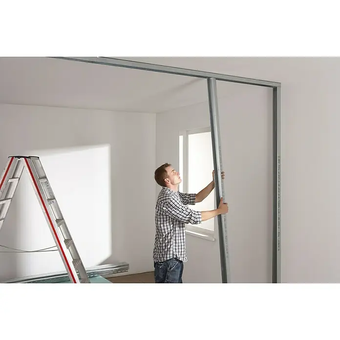 Knauf CW-Standprofil - 3.500 x 75 x 50 mm, Stahl - Mann montiert Trockenbauwand mit Metallprofilen in einem hellen Raum. Eine Leiter steht im Hintergrund.