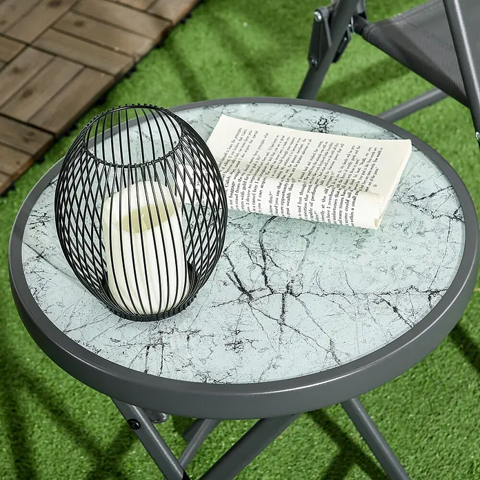Outsunny Garten-Beistelltisch - L x B x H: 45 x 45 x 50 cm, Weiß - Runder, grauer Gartentisch mit gemusterter Glasplatte, darauf eine schwarze Laterne und ein Buch.