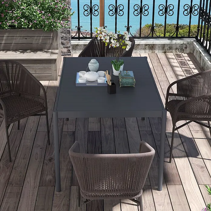Furnicato Gartentisch - L x B x H: 145 x 90 x 74 cm, Rechteckig, Dunkelgrau - Outdoor-Essgarnitur: dunkler grauer quadratischer Tisch mit vier braunen geflochtenen Stühlen auf einem Holzbalkon mit Meerblick.