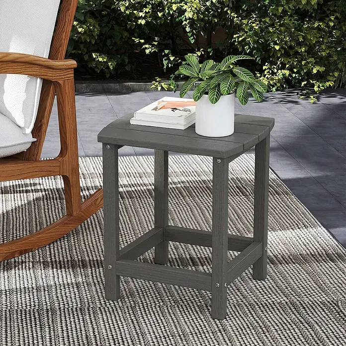 Outsunny Garten-Beistelltisch - L x B x H: 48 x 37 x 46 cm, Grau - Dunkelgrauer Outdoor-Beistelltisch mit Büchern und Pflanze neben einem Holzschaukelstuhl auf einem Teppich.