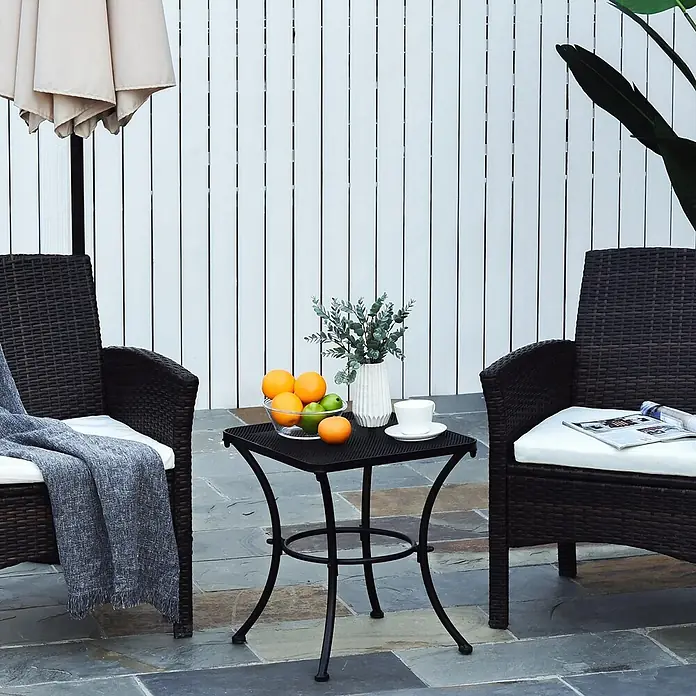 Outsunny Garten-Beistelltisch - L x B x H: 45 x 45 x 50 cm, Schwarz - Outdoor-Terrassenmöbel-Set mit zwei braunen Korbstühlen, weißen Kissen und einem schwarzen Metall-Beistelltisch.