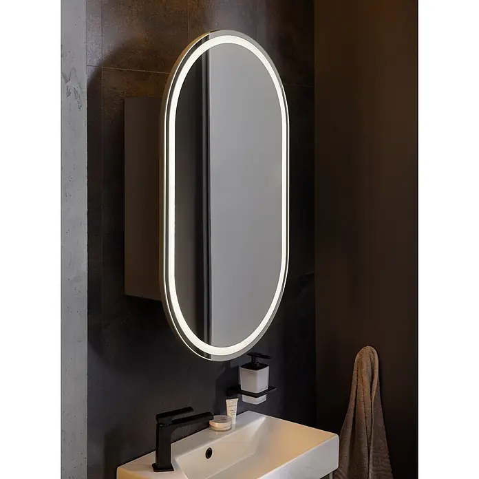 Camargue LED-Spiegelschrank - B x H: 54 x 90 cm, Holz, Anthrazit, DIN Anschlag: Links - Ovaler LED-Spiegel mit beleuchtetem Rahmen über einem weißen Waschbecken und schwarzem Wasserhahn im Badezimmer.