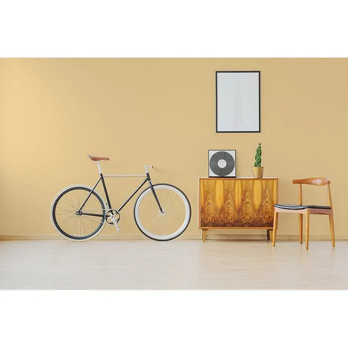 Livingwalls Wandfarbe Gelb Gentel Ginger 5004 5l - Matt, 5 l - Stilvolles schwarzes Fixie-Fahrrad mit weißen Rädern und braunem Ledersattel, in einem modernen Raum an einer gelben Wand gelehnt.