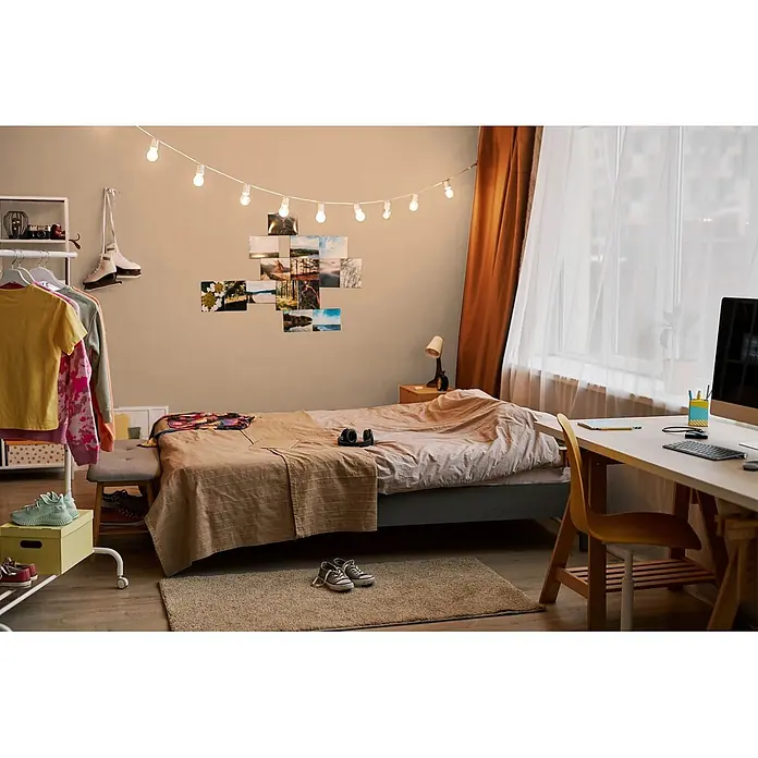 Livingwalls Wandfarbe Beige Sandy Beige DD126085 1l - Beige, Matt, 1 l - Gemütliches, helles Schlafzimmer mit Bett, Schreibtisch und dekorativen Lichterketten.