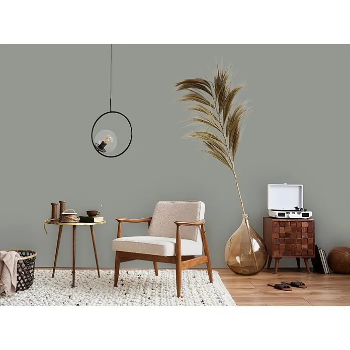 Livingwalls Wandfarbe Grau Original Oregano 4014 2,5l - Matt, 2,5 l - Gemütliches Wohnzimmer mit beigem Sessel, rundem Beistelltisch und Plattenspieler auf Holzschrank, auf einem Strukturtäppich.