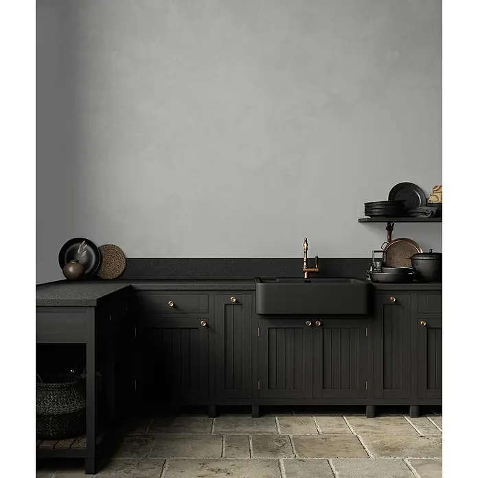 Livingwalls Wandfarbe Grau Creamy Grey DD125763 5l - Grau, Matt, 5 l - Rustikale schwarze Küchenschränke mit Messingakzenten und schwarzem Spülbecken unter grauer Wand auf Steinboden.