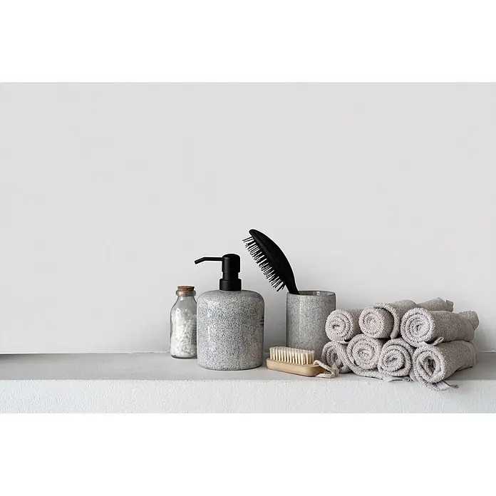 Livingwalls Wandfarbe Grau Asian Noodles 1002 2,5l - Matt, 2,5 l - Gesprekelter grauer Keramik-Seifenspender, Glasflasche mit Badesalzen, schwarze Haarbürste in passendem Becher, Holzbürste und gerollte graue Handtücher.