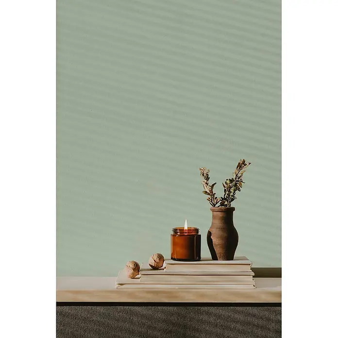 Livingwalls Wandfarbe Grün Soft Green DD125917 1l - Grün, Matt, 1 l - Beleuchtete Kerze in Bernsteinglas, Walnüsse, Vase mit Pflanzen auf Bücherstapel für gemütliche Dekoration.