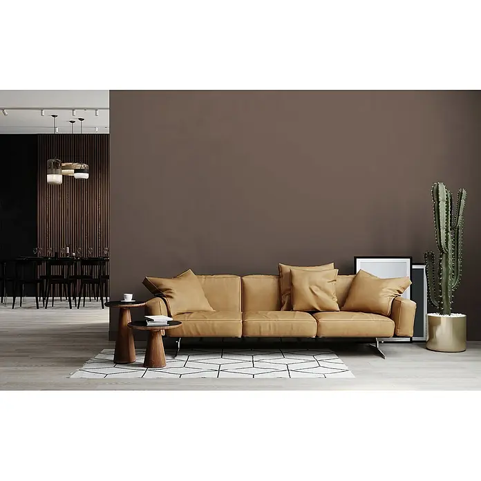 Livingwalls Wandfarbe Braun Soothing Brown DD126069 5l - Braun, Matt, 5 l - Ein beiges Ledersofa mit Kissen steht auf einem geometrischen Teppich in einem modernen Wohnzimmer, flankiert von Holztischen.