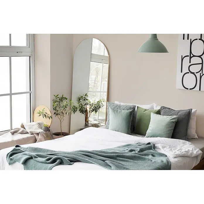 Livingwalls Wandfarbe Creme Sandy Beige DD126070 1l - Creme, Matt, 1 l - Mintgrüner Stricküberwurf und Zierkissen auf einem weißen Bett in einem hellen Schlafzimmer.