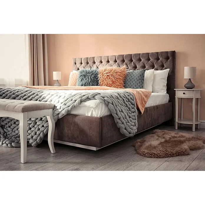 Livingwalls Wandfarbe Rosa Diverse Apricot DD126174 5l - Rosa, Matt, 5 l - Bett mit dunkel getuftetem Kopfteil, passendem Rahmen, grobmaschiger grauer Strickdecke und farbigen Akzentkissen in einem gemütlichen Schlafzimmer.
