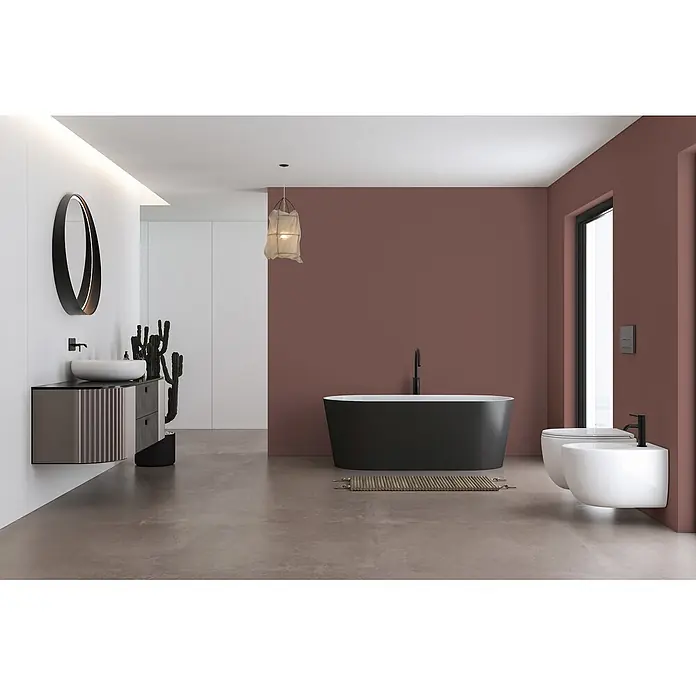 Livingwalls Wandfarbe Braun Rosy Beige DD125853 5l - Braun, Matt, 5 l - Modernes Badezimmer mit schwarzer freistehender Badewanne, weißem Wand-WC, Bidet und Waschtisch mit Spiegel, vor einer bordeauxroten Akzentwand.