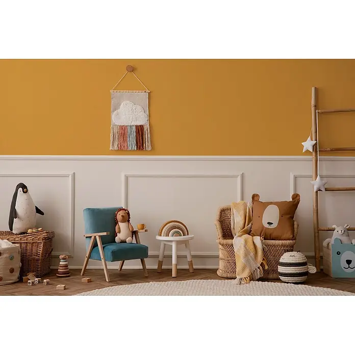 Livingwalls Wandfarbe Gelb Sunny Yellow DD126112 1l - Gelb, Matt, 1 l - Gemütliches Kinderzimmer mit blauen und geflochtenen Stühlen, Plüschtieren und einem Regenbogen-Wandteppich an gelber Wand.