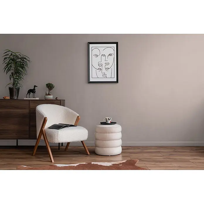 Livingwalls Wandfarbe Beige Rosy Beige DD125841 5l - Beige, Matt, 5 l - Cremefarbener Bouclé-Sessel mit Holzbeinen in einem gemütlichen Wohnzimmer, neben einem runden cremefarbenen Hocker.