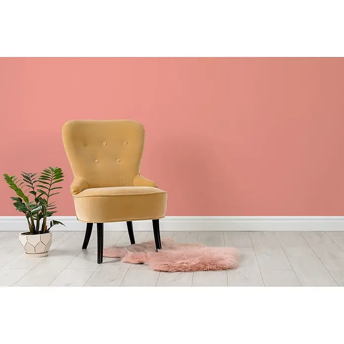 Livingwalls Wandfarbe Pink Georgeous Grapefruit 7004 2,5l - Pink, Matt, 2,5 l - Gelber Samtsessel mit getufteter Rückenlehne und schwarzen Beinen, in einem modernen Raum mit Pflanze und rosa Teppich.