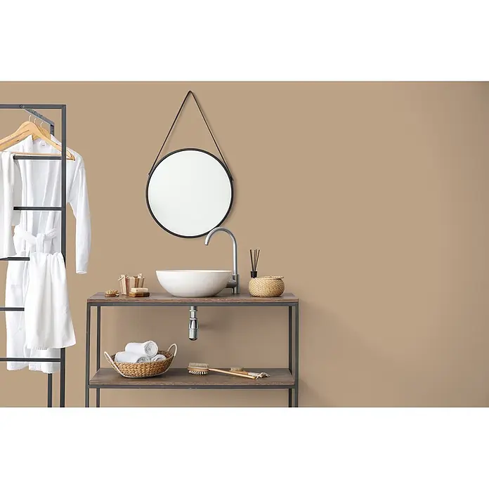 Livingwalls Wandfarbe Braun Friendly Fennel 6005 5l - Matt, 5 l - Moderne Badmöbel-Waschtischanlage mit weißem Waschbecken, silbernem Wasserhahn, rundem Spiegel. Weiße Bademäntel und Handtücher an schwarzem Metallregal.