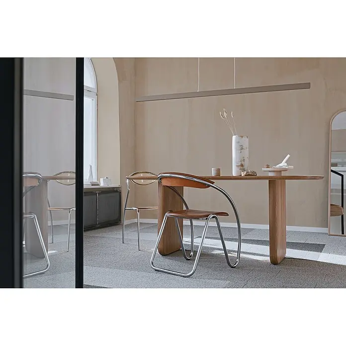 Livingwalls Wandfarbe Creme Sandy Beige DD126074 2,5l - Creme, Matt, 2,5 l - Ein modernes Esszimmer mit warmem Holztisch und Stühlen mit Chromrahmen und braunen Ledersitzen, unter einer eleganten linearen Pendelleuchte.