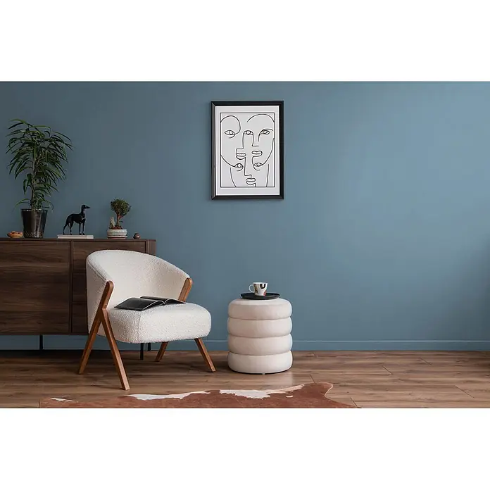 Livingwalls Wandfarbe Blau Ocean Blue DD125893 1l - Blau, Matt, 1 l - Cremefarbener Bouclé-Sessel mit Holzbeinen, neben passendem zylindrischem Hocker, in einem modernen Wohnzimmer.
