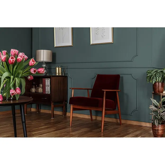 Livingwalls Wandfarbe Grün Soft Green DD125934 5l - Grün, Matt, 5 l - Elegantes Wohnzimmer mit dunkelgrünen getäfelten Wänden, einem roten Samtsessel und Holzmöbeln.