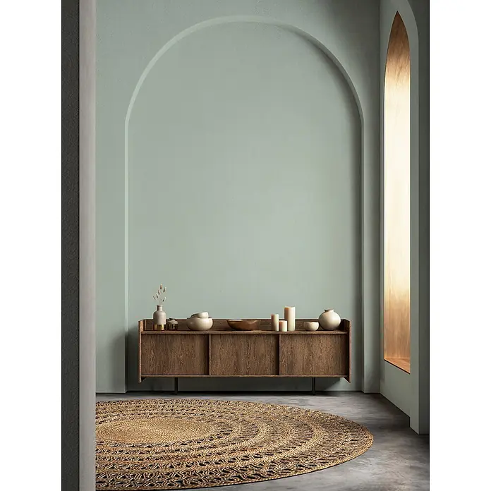 Livingwalls Wandfarbe Grün Soft Green DD125921 2,5l - Grün, Matt, 2,5 l - Runder, gewebter Juteteppich mit dunklen Akzenten auf Betonboden in minimalistischem Raum.