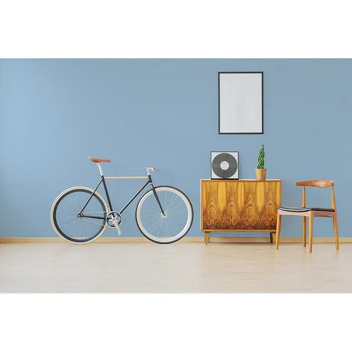 Livingwalls Wandfarbe Blau Soft Sky 3003 5l - Matt, 5 l - Ein schwarzes Fahrrad mit weißen Rädern und braunem Sattel lehnt an einer blauen Wand in einem modernen Raum.