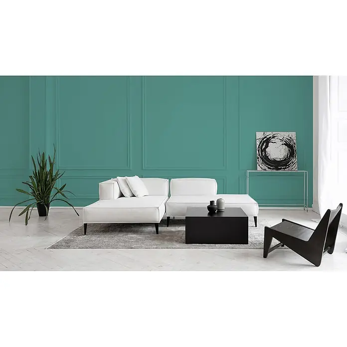Livingwalls Wandfarbe Blau Emerald Green DD125939 2,5l - Blau, Matt, 2,5 l - Ein geräumiges Wohnzimmer zeigt ein weißes L-förmiges Ecksofa und einen schwarzen quadratischen Couchtisch auf einem Teppich. Ein schwarzer Holz-Loungesessel ergänzt das moderne Ambiente.