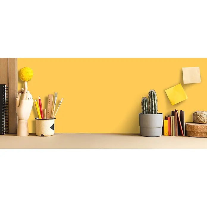 Livingwalls Wandfarbe Gelb Mighty Mango 5003 2,5l - Matt, 2,5 l - Ein hellbrauner Schreibtisch mit einer Holzhand, Bleistiften, Pinseln, zwei Kakteen in einem grauen Topf, Büchern, Bindfaden und Haftnotizen an einer gelben Wand.