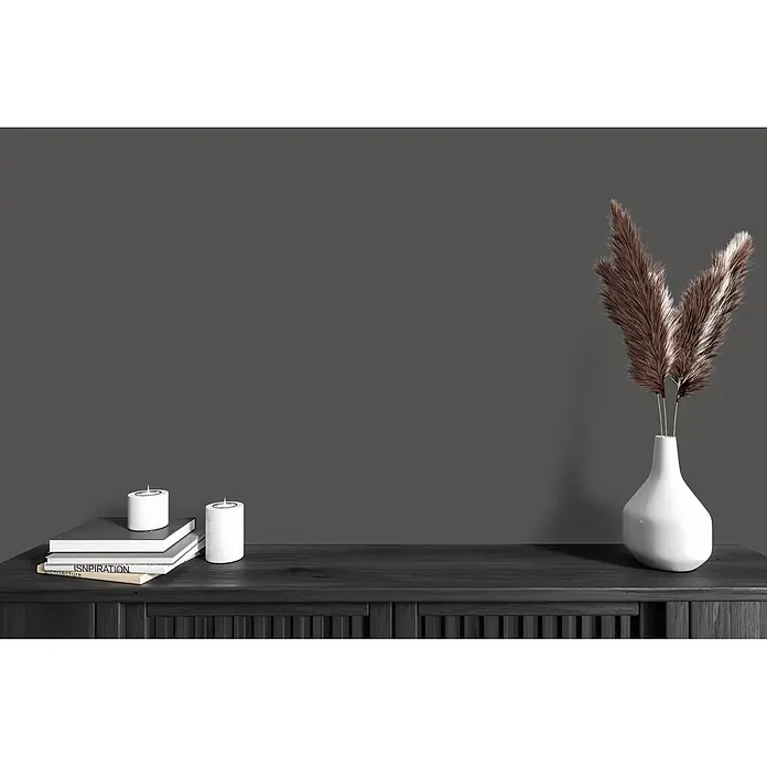 Livingwalls Wandfarbe Grau Poppy Seed 1014 2,5l - Matt, 2,5 l - Dunkle Holzkonsole mit weißen Kerzen auf Büchern und einer weißen Vase mit getrocknetem Gras.